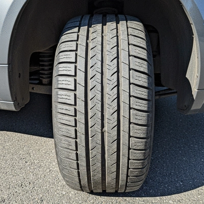 Close-up of a car tire with visible wear patterns on a road