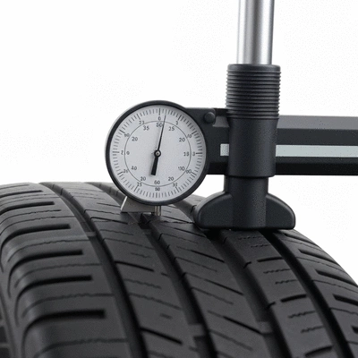 Gros plan sur un pneu de voiture avec une jauge de profondeur de bande de roulement